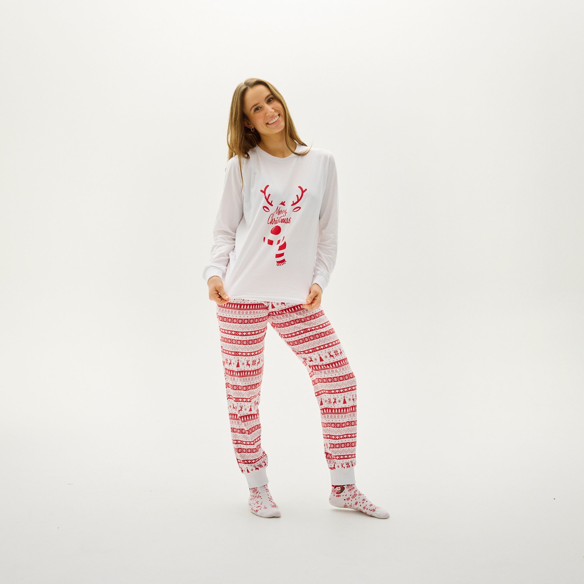 Weihnachtspyjama Damen mit rotem Rentiermotiv auf weißem Oberteil und roten Musterhosen.